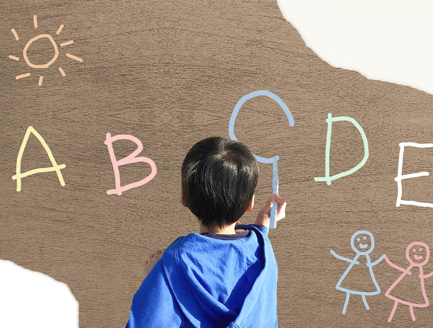 壁にアルファベットを描く子ども