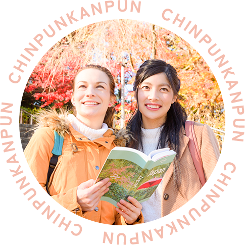 紅葉の中で日本のガイドブックを見る日本人女性と外国人女性
