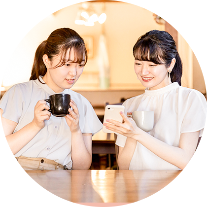 カフェでスマートフォンを見ながら談笑する2人の女性